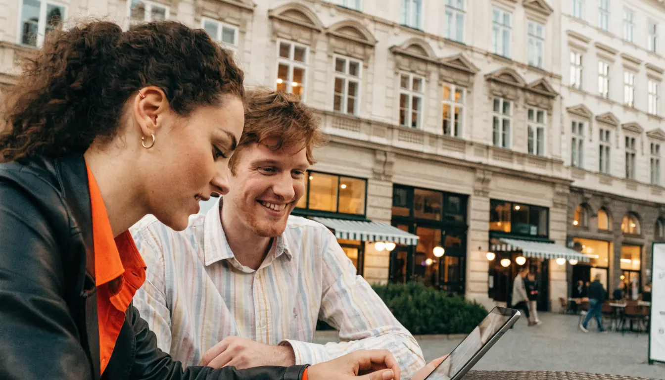 Junges Paar im Wiener Café, Tablet mit Bonusanzeige, Abendbeleuchtung